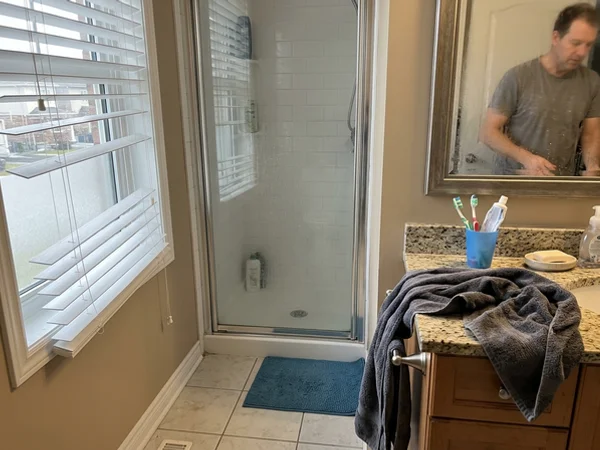 Bathroom-grade faux wood blind beside a shower in a Barrhaven ensuite