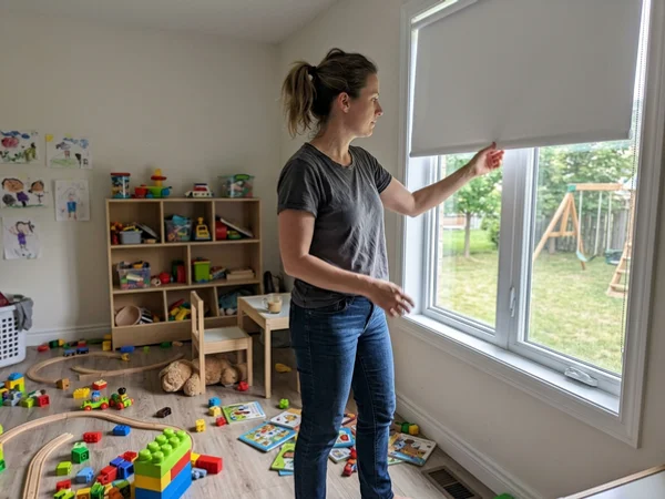 Parent lifting a cordless roller blind by the bottom rail in a Stittsville playroom